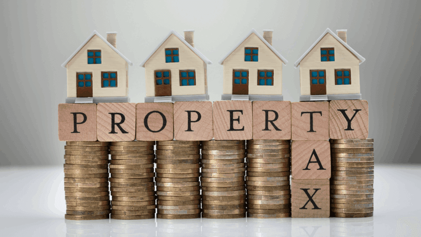 Property tax concept with stack of coins and house models