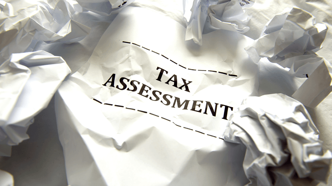 Tax assessment with crumpled papers around it