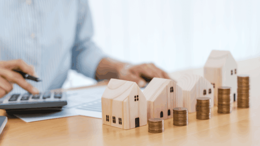 Tax planning using calculator with miniature homes and coins