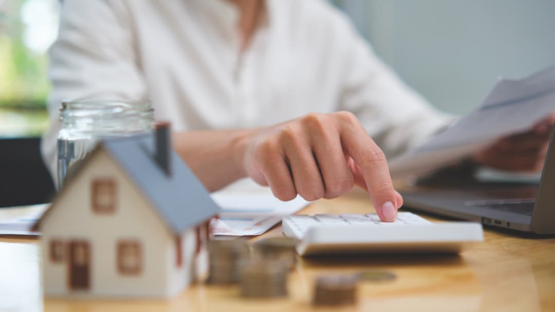 Homeowner calculating property tax costs beside a small house model