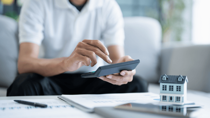 Homeowner calculating rising property tax costs beside a house model
