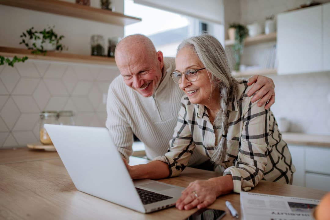 Older couple reviewing property tax information on a laptop at their kitchen table.